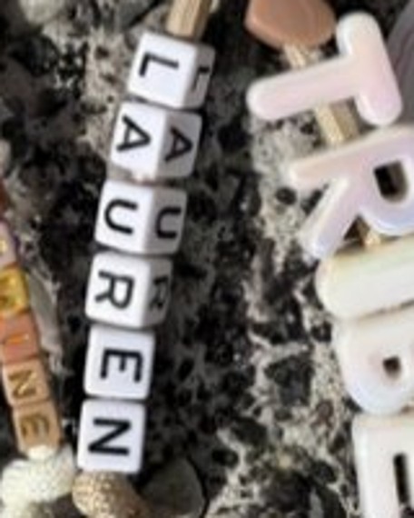 Small square letter beads spelling Lauren in white with black letters